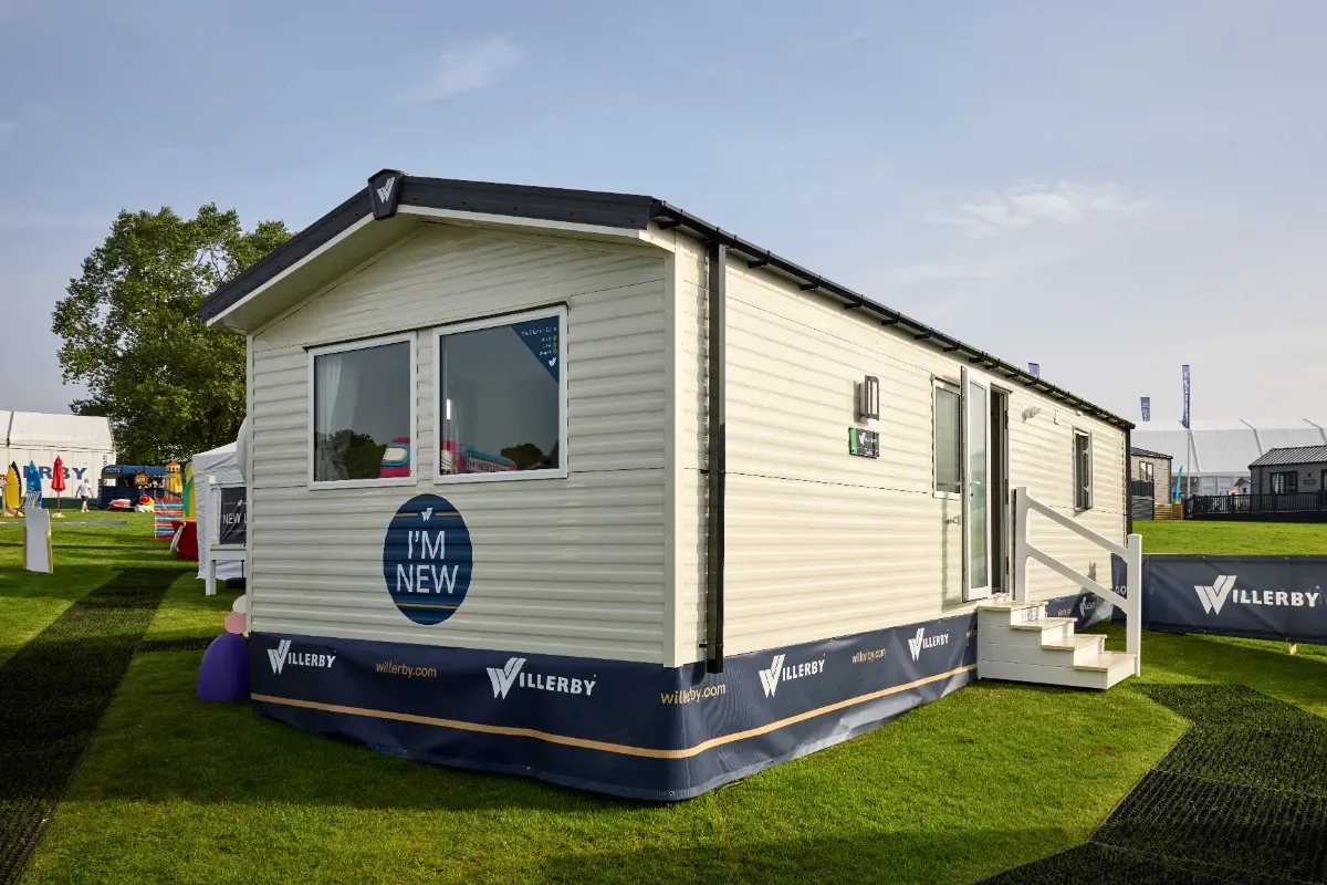 A Willerby Ellerton entry level holiday home. It has cream cladding, black roof and a sign that says ‘I’m new’. 