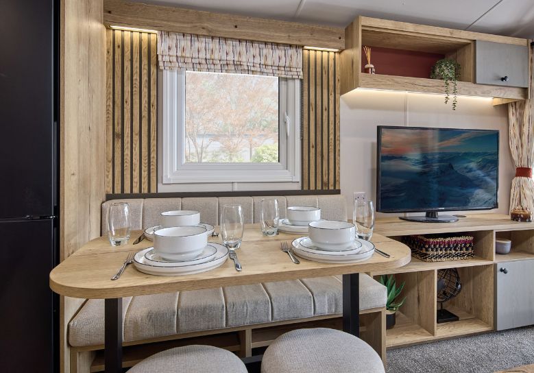 The Willerby Rio Compact dining area has an oak effect acoustic accent wall with cream seating.