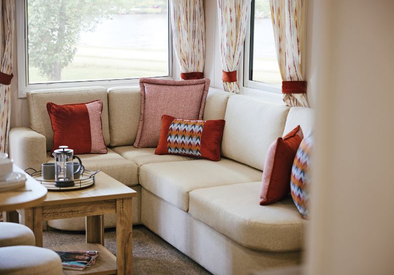 The Willerby Rio Compact lounge has a fixed corner sofa with orange patterned cushions.