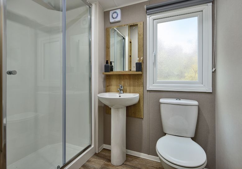 The Willerby Rio Compact family shower room has oak effect unit with a cream accent wall.