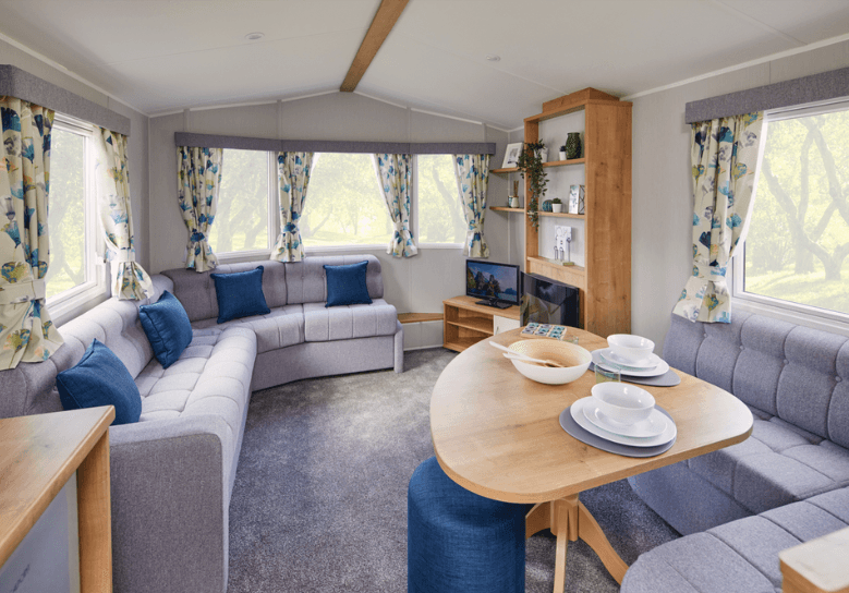The Willerby Ashurst lounge adorned with grey corner seating for both lounge and diner, and blue pillows matching the stool and curtains.