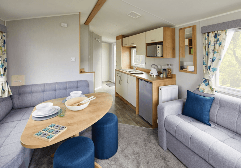 The Willerby Ashurst dining area with a grey corner seating and two blue stools surrounding a curved corner table. 