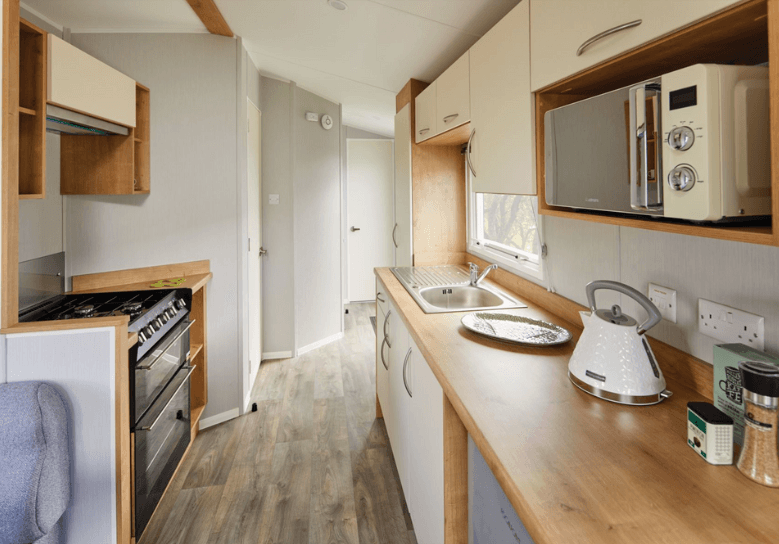 The Willerby Ashurst has a two sided kitchen with cream cabinet doors enhanced on the oak effect units.