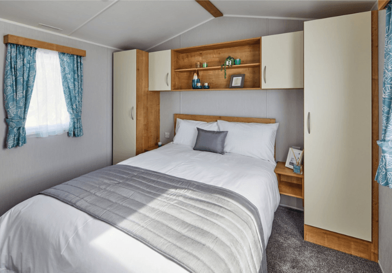 The Willerby Ashurst cosy master bedroom with overhead storage units with cream cabinet doors.