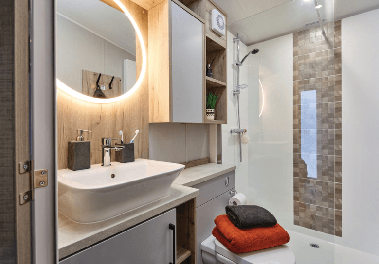 The Willerby Astoria bathroom with an LED heated round mirror, oak effect storage units and a walk-in shower.
