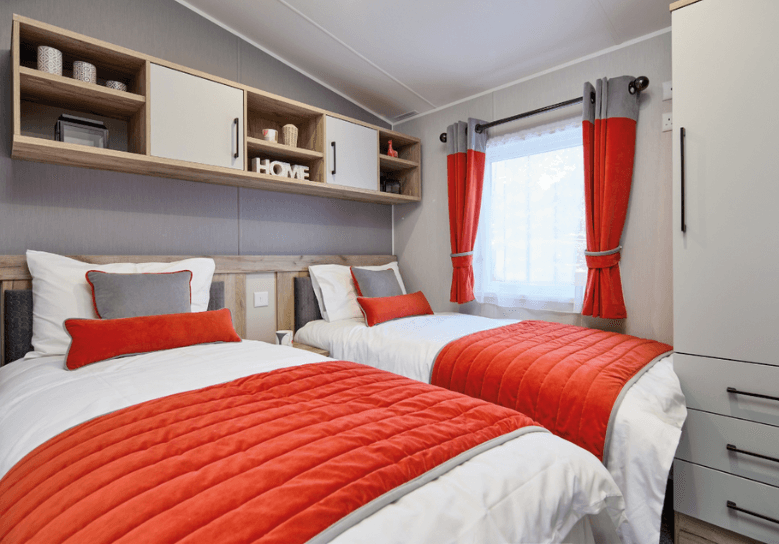 The Willerby Astoria twin bedroom with orange bedding sets and overhead oak effect storage.