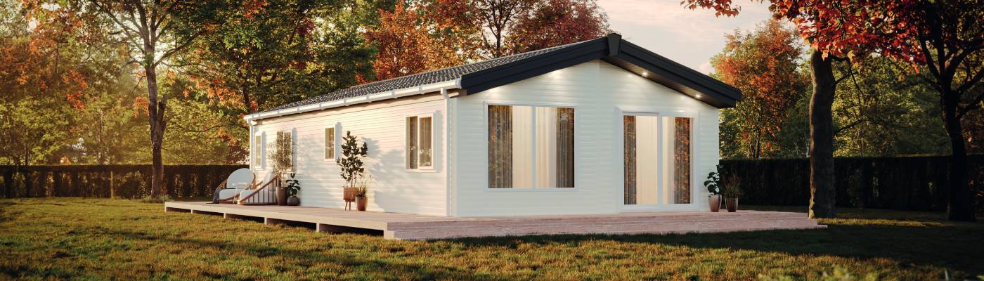 The Willerby Boston is a light coloured holiday lodge on a spacious plot. The season is autumn with brown leaves on the trees and golden light. 