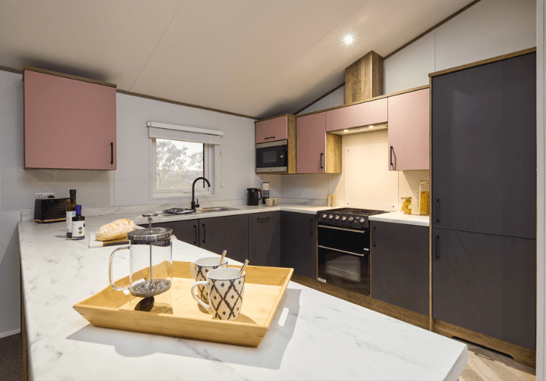 The Willerby Boston kitchen with graphite and blush pink cupboards and white marble effect worktop.