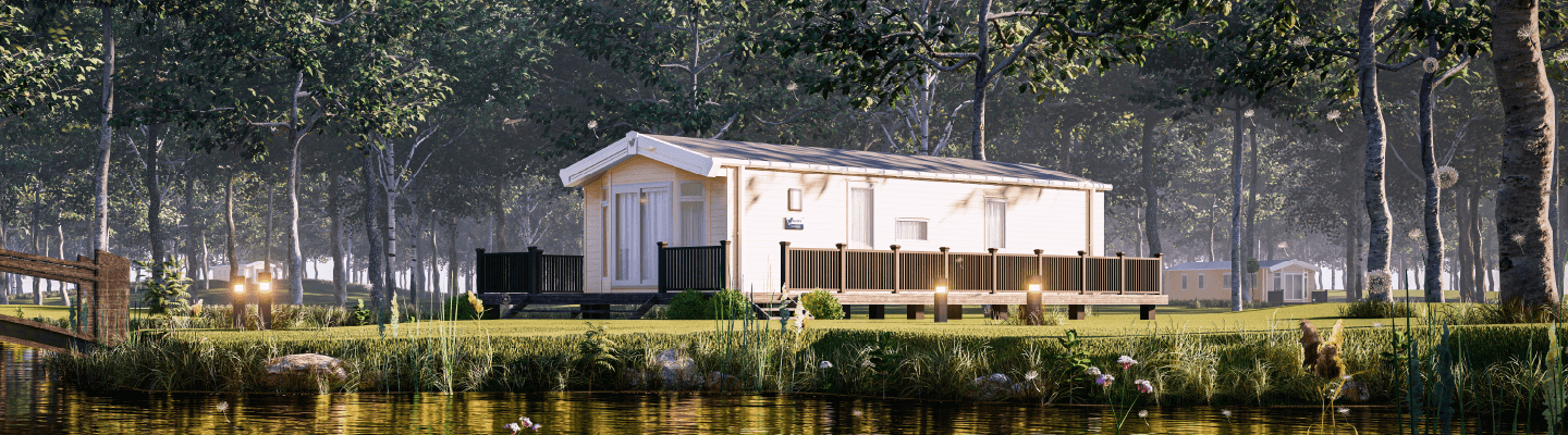 The Willerby Brookwood exterior in cream with a brown decking sat next to a lake.