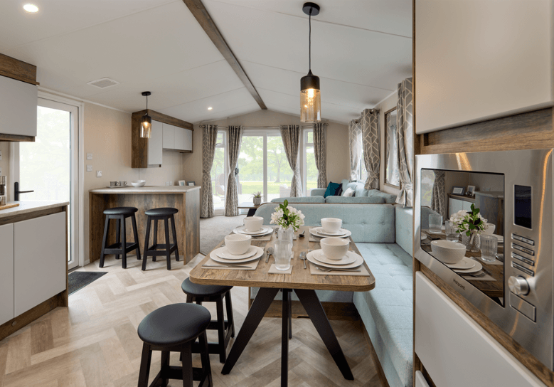 The Willerby Brookwood dining area with sage green fixed L-shaped seating and black stools.