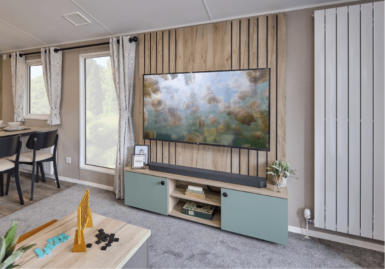 The Willerby Buxton media unit with green cupboard doors and a oak wood effect feature wall.