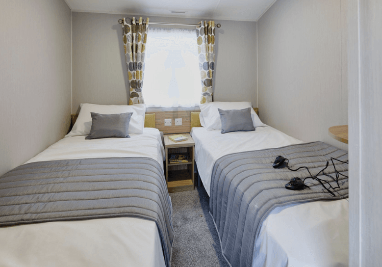 The Willerby Castleton twin bedroom with yellow upholstered headboards and patterned curtains.