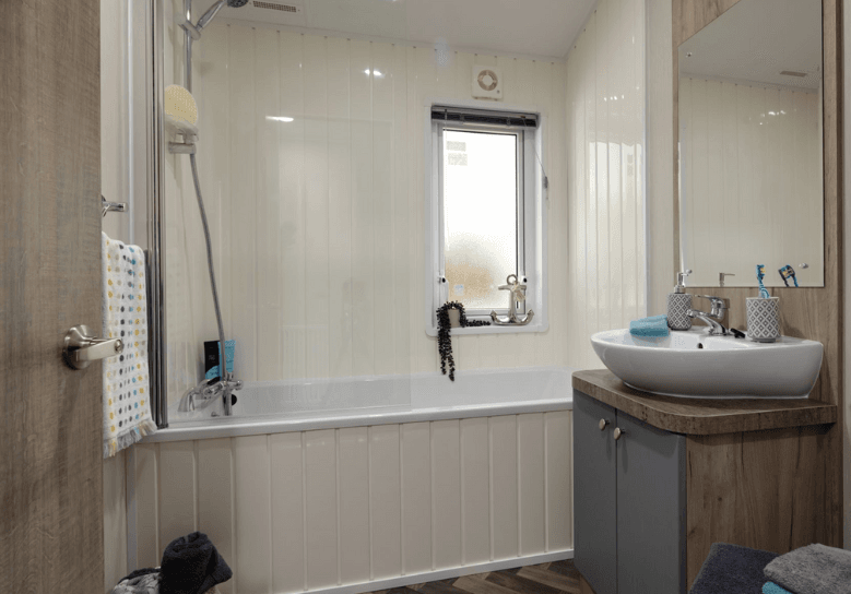 The Willerby Clearwater bathroom with bathtub and a dark wood effect storage unit.