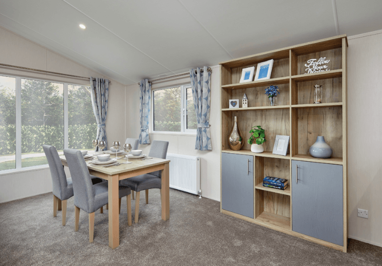The Willerby Clearwater dining area has grey dining chairs and an oak table, and an oak effect ornament cabinet unit with grey cupboard doors.