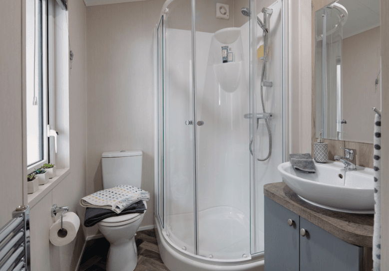 The Willerby Clearwater ensuite with a standing shower with a dark wood effect storage unit.