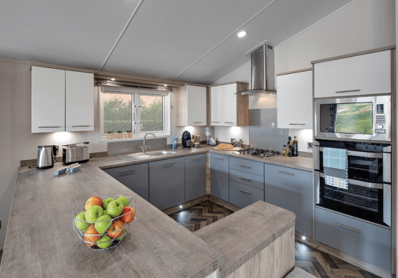 The Willerby Clearwater G-shaped kitchen is adorned with grey and white cupboard doors.