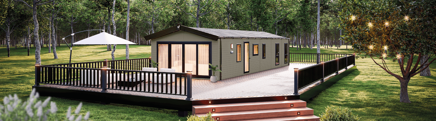 The Willerby Dorchester exterior in environmental green with a wide brown and black decking sited on a grassy field.