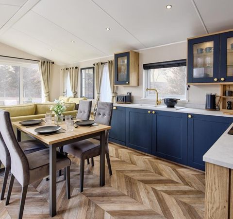 The Willerby Gainsborough contemporary kitchen with a dining oak effect table and grey chairs, and has herringbone wooden effect flooring.