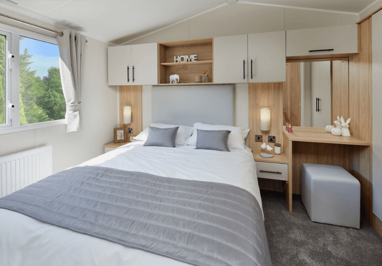 Manor master bedroom with oak overhead storage and side dressing table with white cupboard doors.