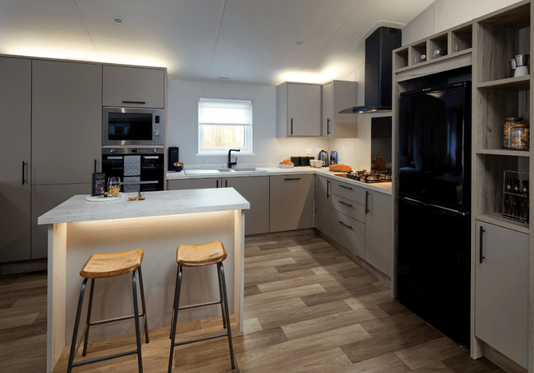 Mapleton L-shaped kitchen with cream cupboard doors and white marble worktops, and a marbled kitchen island with dark oak stools.