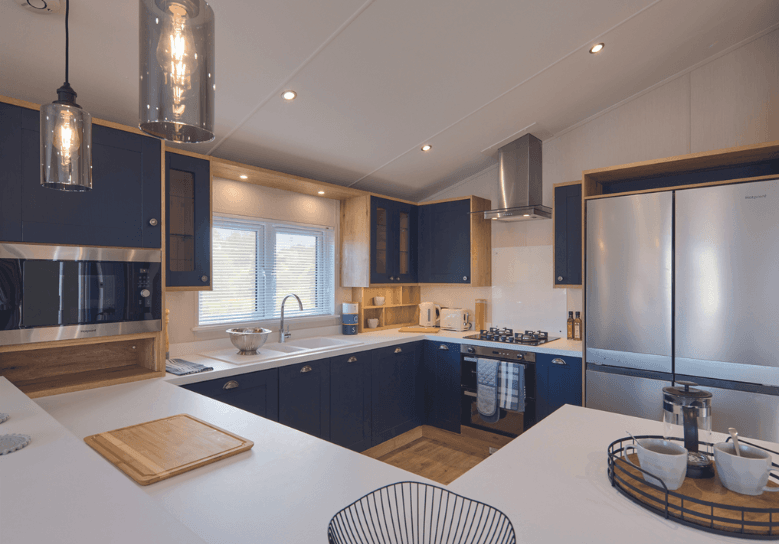 New Holland G-shaped kitchen with white worktops and deep blue cupboard doors.