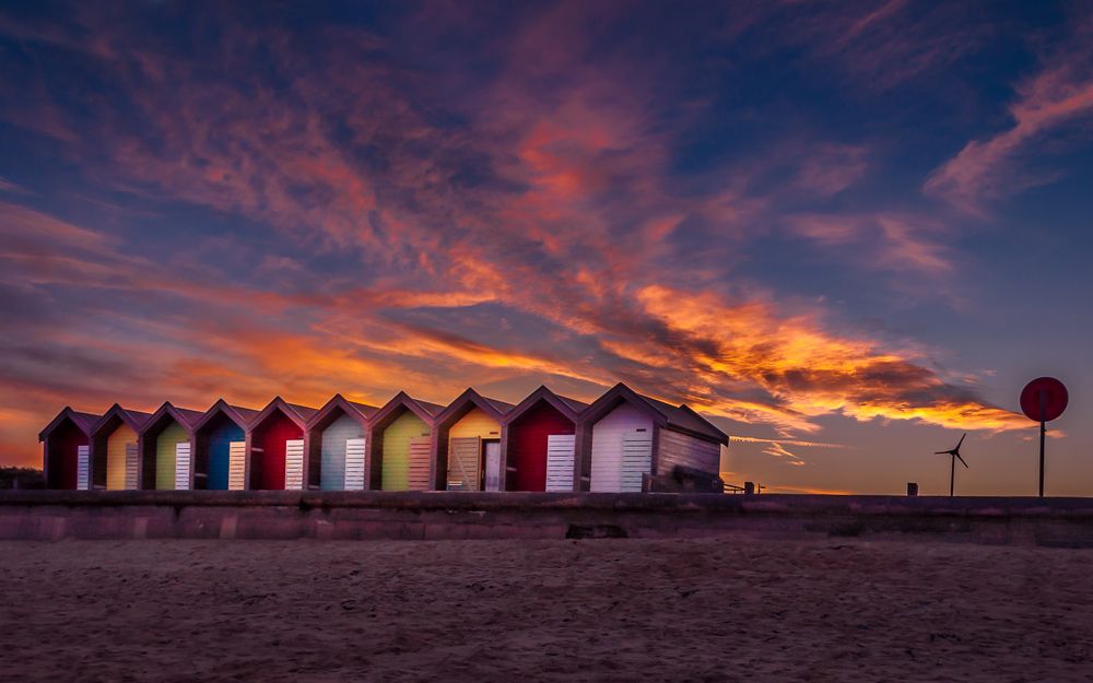 Colourful beach huts by the sea in Blyth, in front of the beautiful sun set