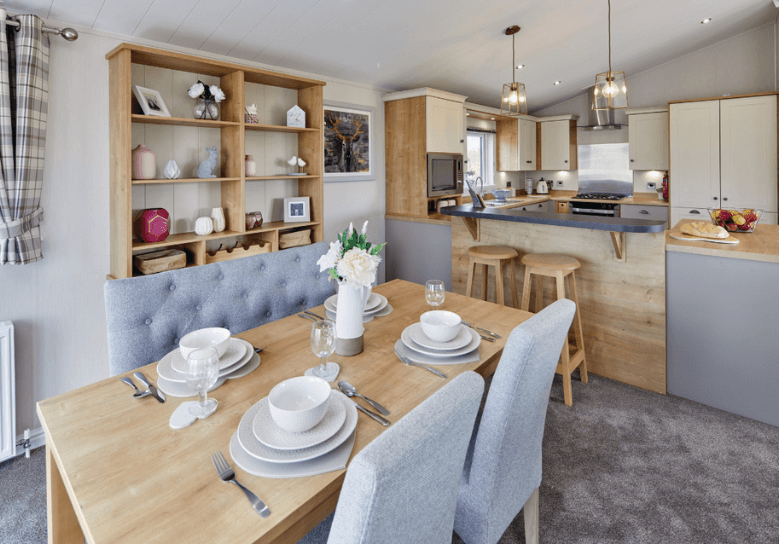 The Willerby Portland dining area has grey chairs surrounding an oak effect table, with an oak effect ornament unit behind.