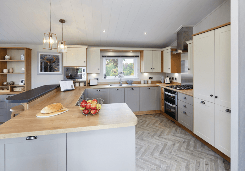 The Willerby Portland G-shaped kitchen has grey and white cupboard doors with an oak effect worktop.