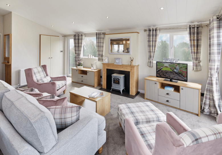 The Willerby Portland lounge has a grey two seater sofa and two pink patterned armchairs, and oak effect storage units throughout.