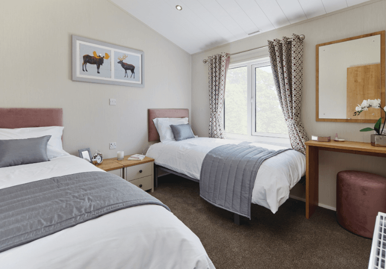 The Willerby Portland twin bedroom has pink upholstered headboards with oak effect bedside tables.