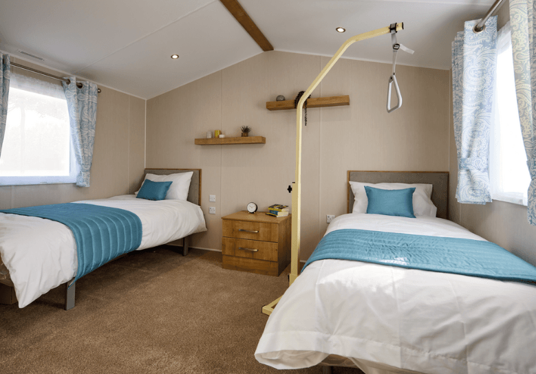 Richmond main bedroom with two single beds in a spacious room, and a lifting aid.