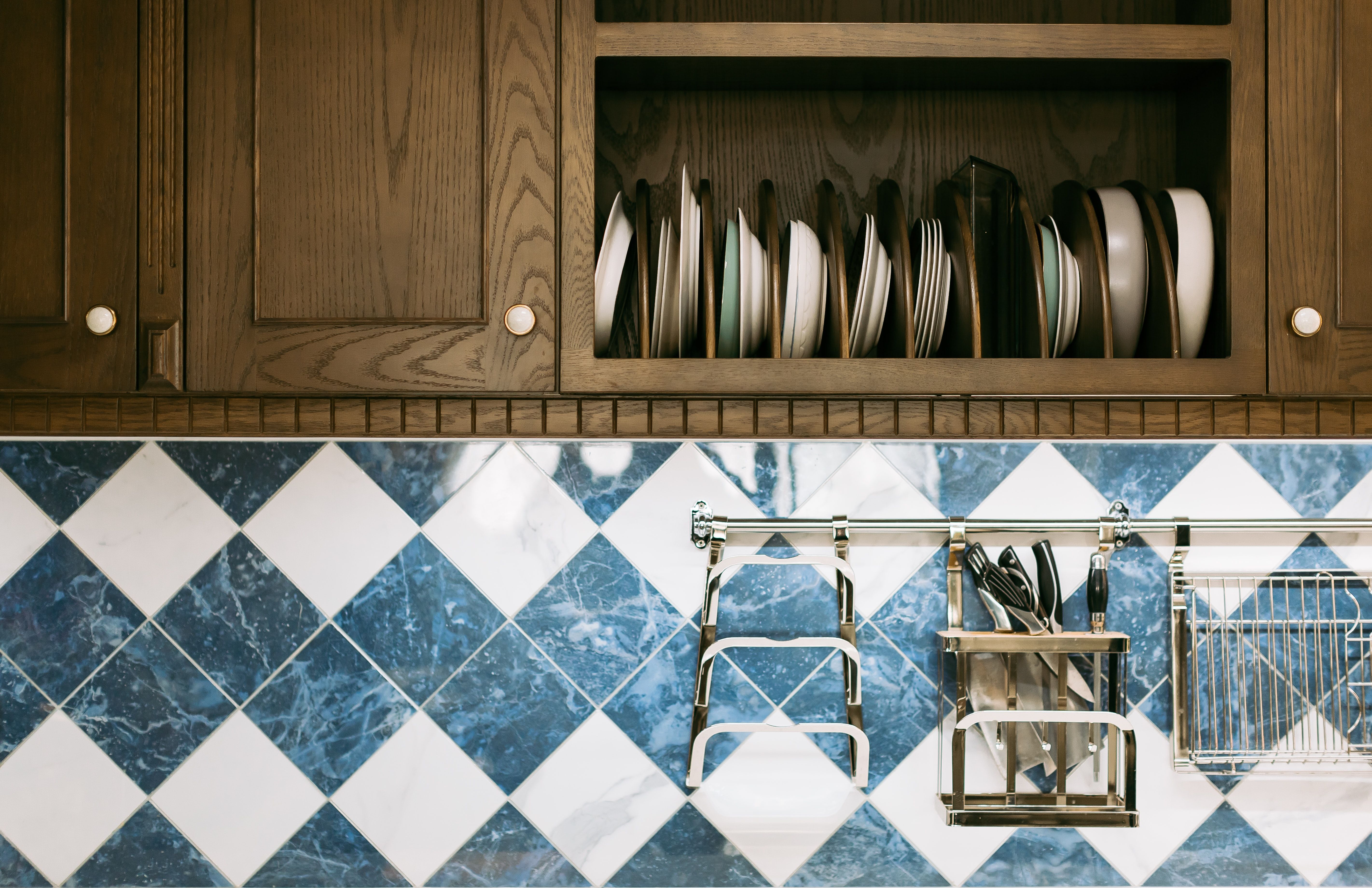 Brown kitchen cupboards above diagonally patterned tiles and metal hanging racks