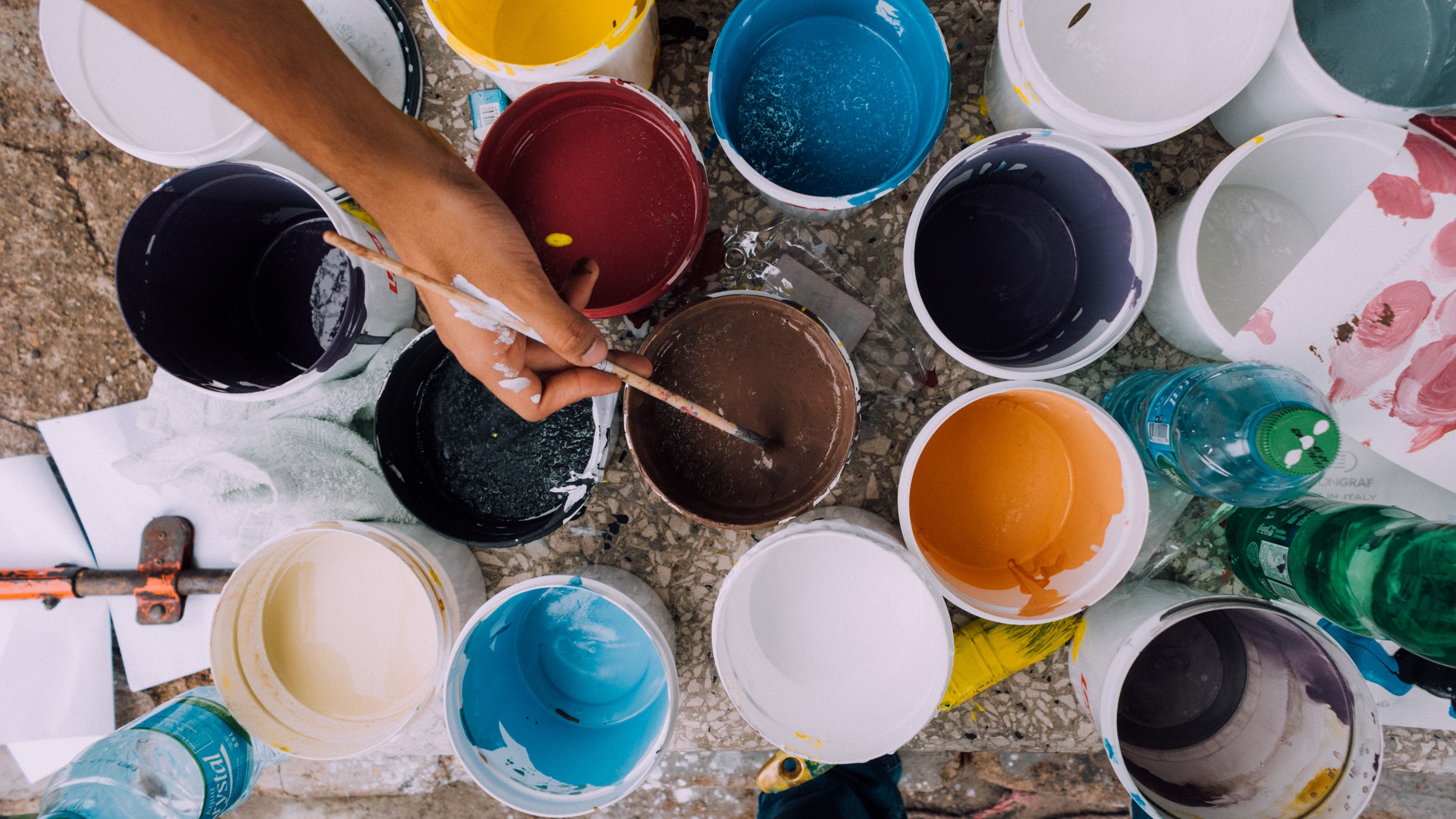 Lots of different coloured tins of paint being used to decorate a caravan