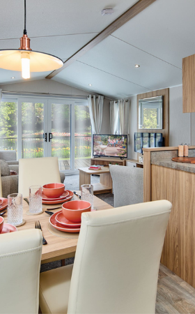 The Willerby Manor dining area has 4 cream chairs surrounding an oak effect table with a window view.