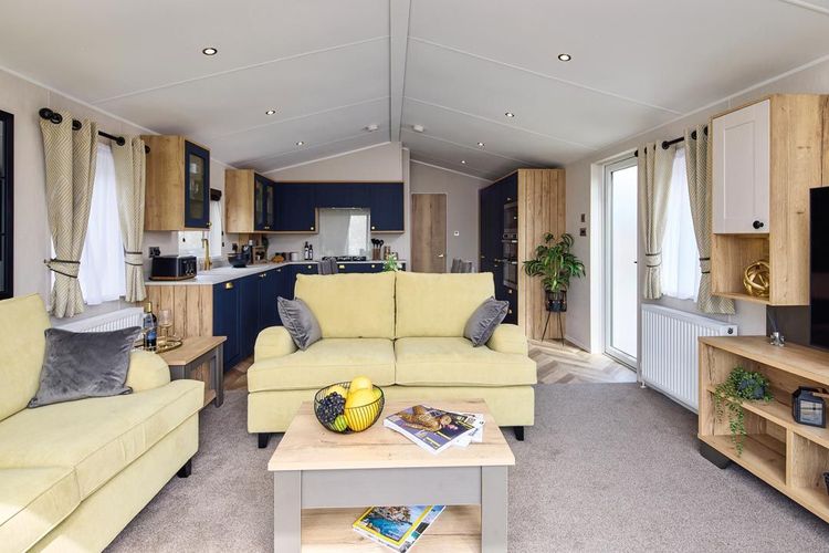 The Willerby Gainsborough lounge has pale yellow freestanding sofas and an oak effect coffee table.