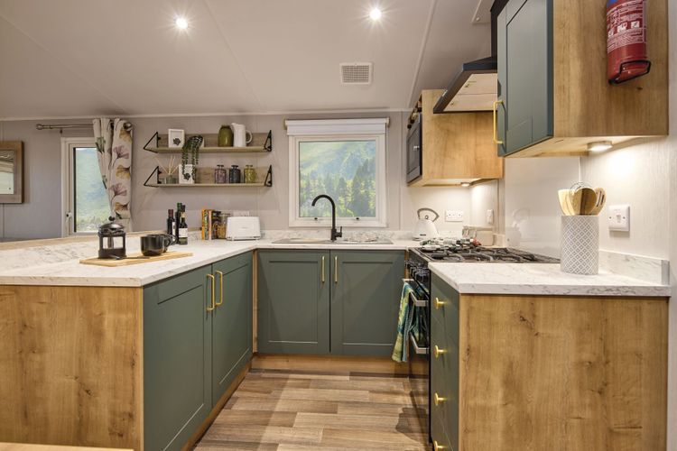 The Willerby Sierra kitchen has oak effect storage units with green cupboard doors and white marble worktop.