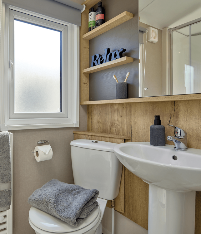 The Willerby Rio family shower room has oak effect storage units along the wall with a cream accent wall.