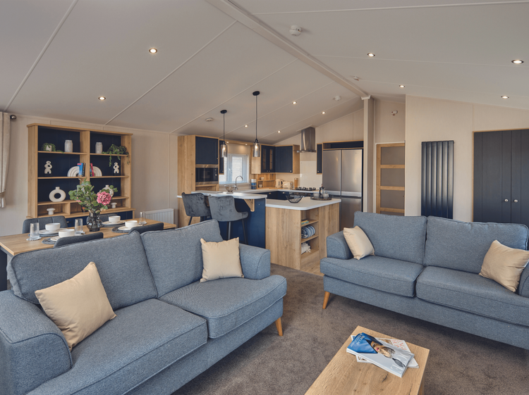 The comfortable free-standing sofas of the Willerby New Holland holiday lodge. Behind them is the open-plan kitchen diner. There is plenty of space. 
