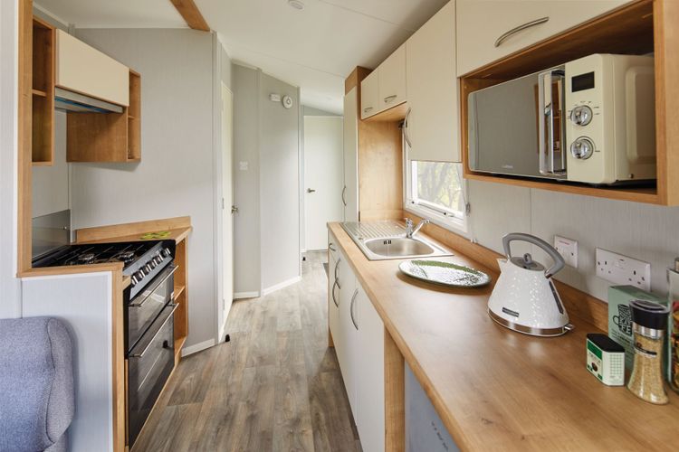 The Willerby Ashurst has a two sided kitchen with cream cabinet doors enhanced on the oak effect units.