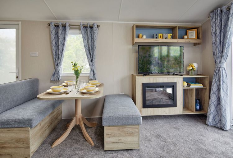 The Willerby Linwood dining area with two grey and oak effect seating and a matching oak effect table, and an oak effect media storage unit with a built in electric fire.