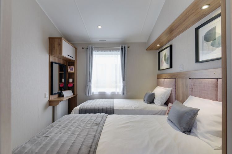 The Willerby Waverley twin bedroom has pink upholstered headboards with oak effect storage units.