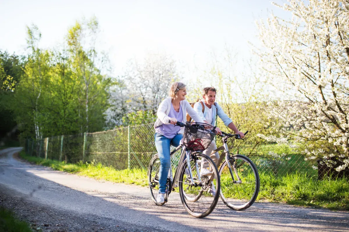 An older couple cycling on a quiet, smooth gravel track in the countryside